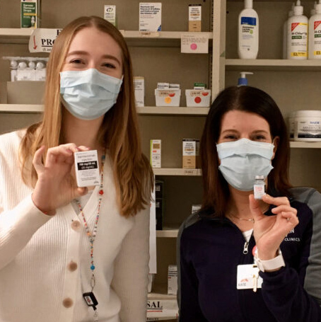 PharmD Rural Health students Anna and Kate hold up vials of COVID vaccine