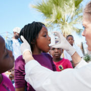 A pharmacy student helps administer an asthma inhaler to a child