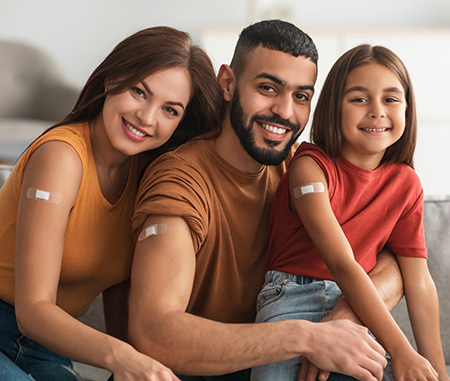 A mom, dad, and their 3rd-grade daughter proudly display their bandaids after getting vaccinated