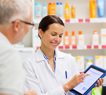 A pharmacist works with a patient to fill in a questionnaire on a tablet